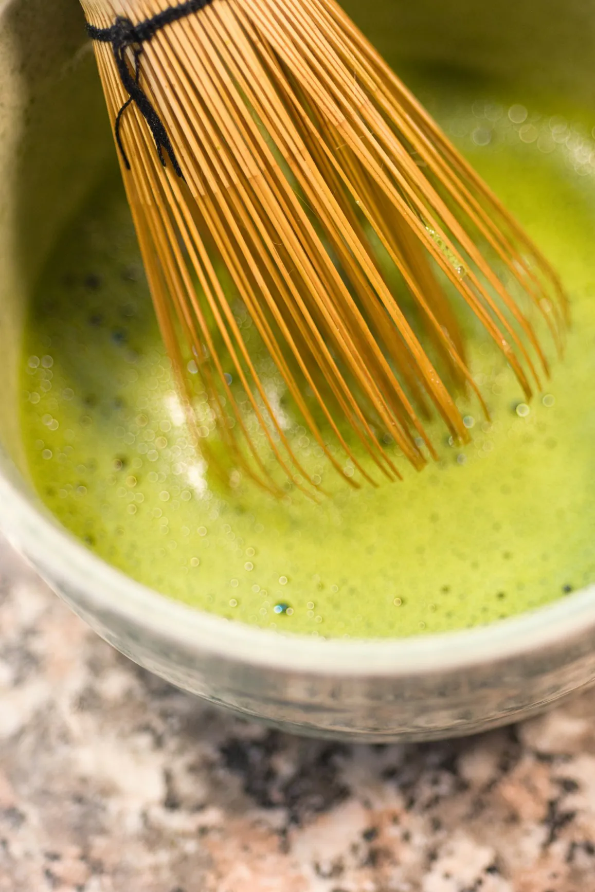 Matcha recién batido con espuma en un tazón de cerámica, con el batidor de bambú dentro