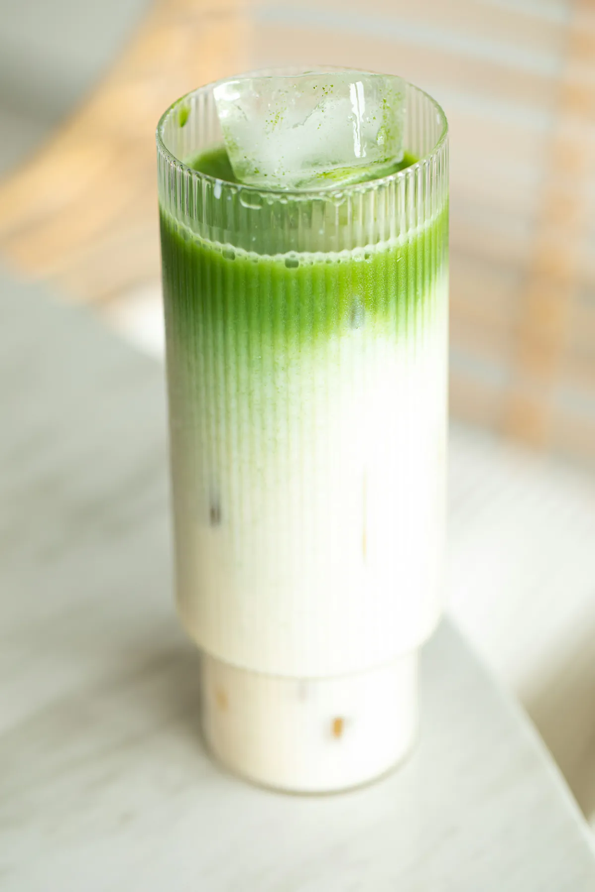 Matcha con hielo en un vaso alto acanalado: el verde del matcha sobre la leche fría